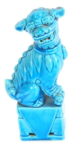 A mid 20thC Chinese porcelain dog of fo, perched on a plinth, with turquoise glaze, 17cm high.