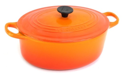 A Le Creuset orange ovenware casserole dish and cover, 30cm wide.