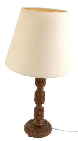 A mid 20thC teak carved table lamp, with leaf design and cream shade, 67cm high. WARNING! This lot contains untested or unsafe electrical items. It is supplied for scrap or re-conditioning only. TRADE ONLY