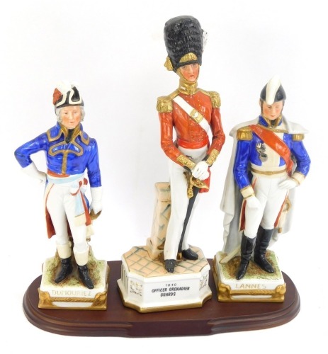 Three porcelain military figures, comprising an 1840 Officer Grenadier Guards, an East German porcelain figure of General Dumouriez, and another of Marshal Lannes, with named plinths, 31cm and 26cm high. (4)