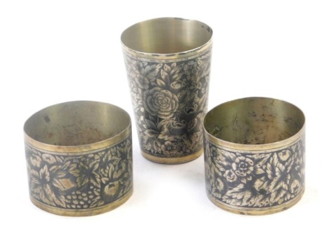 A Russian Soviet era silver beaker, with niello floral and fruit decoration, bearing stamps to underside, 6cm high, and a pair of silver and niello napkin rings 3.67oz. (3)