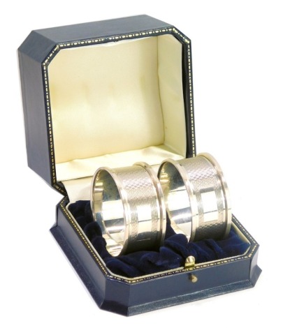 A pair of Elizabeth II silver napkin rings, with engine turned decoration, cased, Birmingham 1994, 0.84oz.