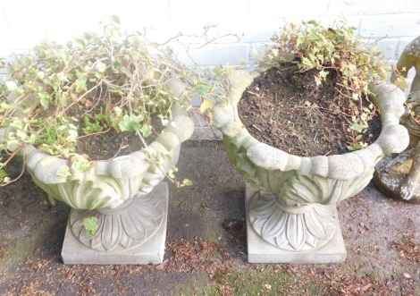 A pair of reconstituted stone garden planters, each with leaf moulded body, on square foot, 46cm high, 50cm diameter.