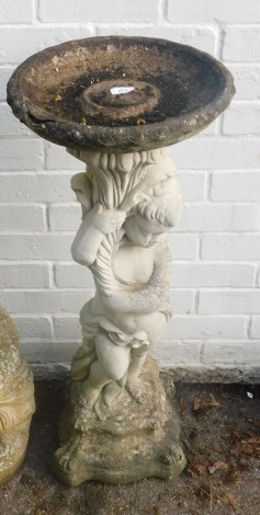 A reconstituted stone bird bath, formed as a child tugging cloth, on a shaped base, 92cm high.