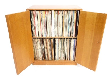 A mid century light oak records cabinet, with two doors opening to reveal a single shelf, enclosing classical LPs and box sets, raised on a plinth base, 75cm high, 61cm wide, 35cm deep.