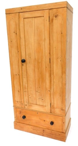 A late 19thC pine single wardrobe, with a panelled door opening to reveal a hanging rail and hooks, over a frieze drawer, raised on a plinth base, 189cm high, 86cm wide, 44cm deep.