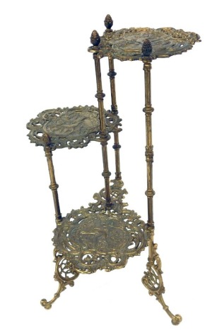 An early 20thC brass three tier plant stand, each tier with embossed bird foliate scroll decoration, raised on fluted columns and rococo style cabriole legs, 74cm high.