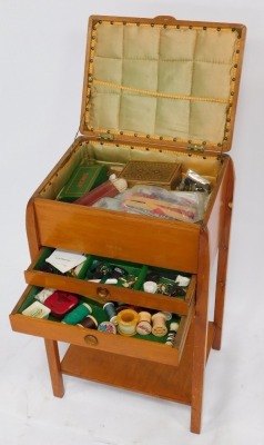 A mid century pine sewing table, the hinged lid opening to reveal a green silk lined interior, over a drop flap, enclosing two frieze drawers, all containing sewing accoutrements, raised on square legs united by an under tier, 66cm high, 39cm wide, 30cm d - 3