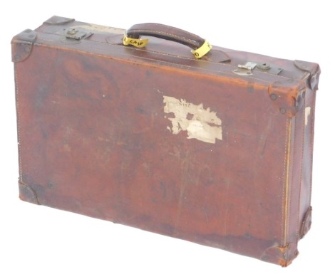 An early 20thC vintage brown leather suitcase, with a fabric lined interior, bears traces of luggage labels, 62cm wide.