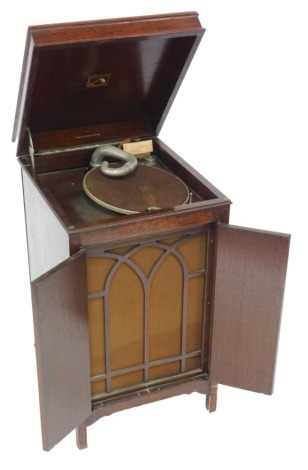 A His Master's Voice oak cased cabinet gramophone, model number 136, with a hinged lid opening to reveal the turntable, above two doors opening to reveal the sound box, and shelf for records, raised on turned legs united by a H framed stretcher, 93cm high