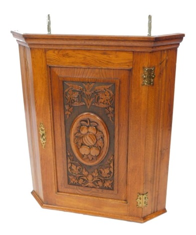 A Victorian oak wall hanging corner cupboard, the panelled door carved with a central oval filled with fruit, in a surround of flowers and foliate scrolls, 82cm high, 71cm wide, 45cm deep.