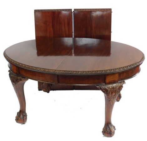 A Victorian mahogany oval wind out dining table, with two additional leaves, raised on foliate carved cabriole legs, on ball and claw feet, 74cm high, 160cm wide, 256cm extended, 102cm deep, with winder, and table covers.