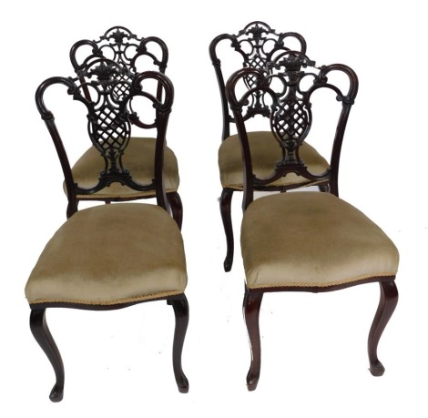 A set of four Victorian mahogany dining chairs, with scroll backs, pierced vase shaped splats, overstuffed in a light brown fabric, raised on slender cabriole legs.