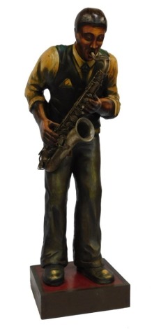 A painted wooden figure of a jazz player, playing a saxophone, raised on a wooden base, 152cm high.