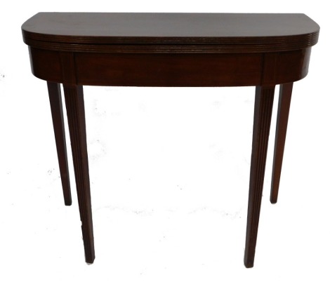 A George III mahogany fold over tea table, with boxwood line inlay, raised on channelled tapering square legs, 73cm high, 86cm wide, 41cm deep.