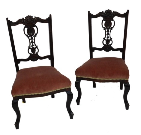 A pair of Victorian mahogany salon chairs, with an acanthus leaf and foliate carved crest rail, similarly carved splat, seat overstuffed in red draylon, raised on cabriole legs.