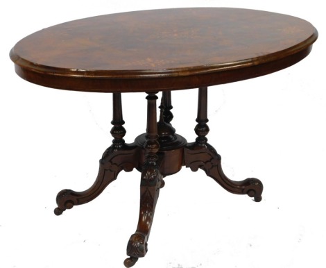 A Victorian walnut and inlaid tilt top oval loo table, raised on turned supports over a circular base with leaf carved cabriole legs, on castors, 70cm high, 122cm wide, 82cm deep.