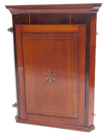 A Georgian mahogany and rosewood hanging corner cabinet, the outswept pediment over a single door with oval paterae inlay, opening to reveal three shelves, raised on a plinth base, 92.5cm high, 72cm wide, 35cm deep.