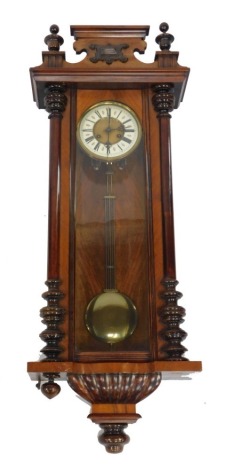 A late 19thC mahogany and walnut cased Vienna wall clock, circular brass dial with enamel chapter ring bearing Roman numerals, eight day movement, the case with a shaped pediment, above a front flanked by turned pilasters, over a semi fluted base, with pe