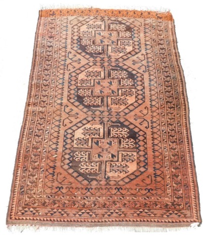 An Afghan red ground rug, with three central medallions bearing foliate motifs, within a repeating foliate and geometric border, 163cm x 106cm.