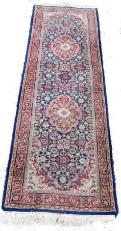 A Kurdish blue ground runner, decorated with two central medallions, within a floral ground and repeating floral and geometric borders, 235cm x 78cm.