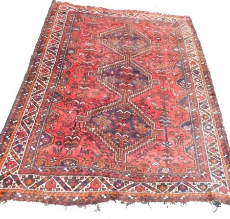 A Persian Shiraz red ground rug, with central geometric motifs, within a ground of flowers, animals and birds, within repeating geometric borders, 210cm x 178cm.