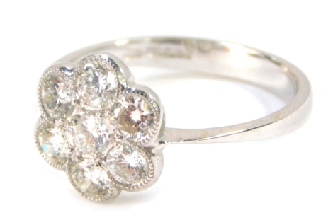 An 18ct gold and diamond cluster ring, set with seven round brilliant cut diamonds, each stone 2.4mm x 2.4mm x 1.8mm, each approx 0.12ct, each in a rub over setting formed as a flower, size N 1/2, 2.6g all in.