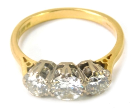 An 18ct gold and three stone diamond dress ring, with three round brilliant cut diamonds, the central stone, 5.4mm x 5.4mm x 2.4mm, totalling approx 0.44ct, flanked by two smaller stones, each 4.2mm x 4.2mm x 3.4mm, each totalling approx 0.27ct, in a doub