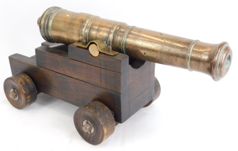 A 19thC brass table cannon, numbered 5, on a stepped wooden base, 23cm high, 31cm wide.