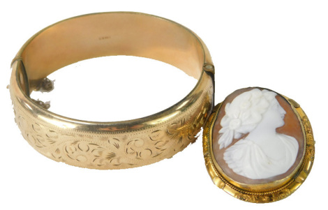 Two items of jewellery, comprising a pinchbeck framed cameo brooch, and a Victorian hinged bangle, of floral design, stamped 9ct metal core, 35.1g all in. (2)