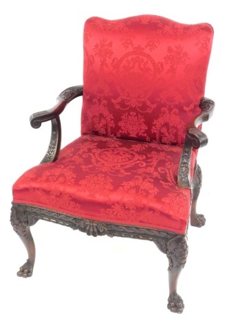 A 19thC mahogany open armchair, with red damask upholstery, carved and scroll arms, and cabriole legs with paw feet, 75cm over arms.