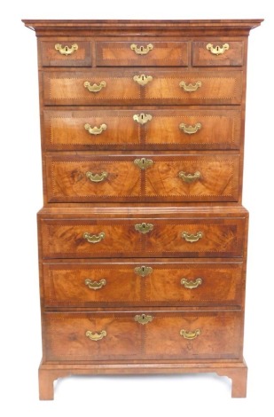 A George III figured walnut and cross banded tallboy or chest on chest, with moulded cornice and arrangement of three over three drawers to the upper part and three graduated drawers to the lower, each with brass solid back plate loop handles and escutche