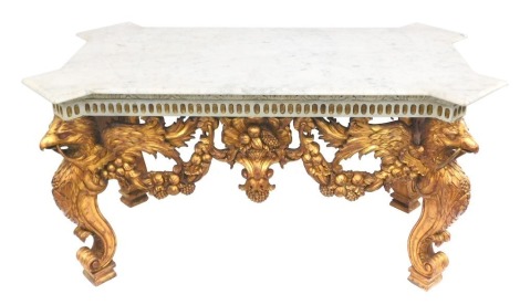 A centre table in the manner of William Kent, with white marbled top, over a gilt and painted frame with eagle monopodia legs, with the wings holding bacchanalia, vines, and fruits, 92cm high, 180cm wide, 100cm deep.