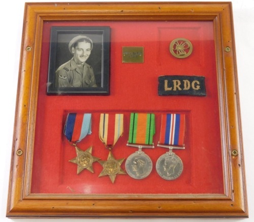 A cased military medal group, with LRDG material badge, RDG Scorpion badge, and four World War II style medals, in a case bearing mark PTE A. BARNS LRDG, the case 32cm x 31cm.