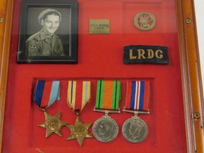 A cased military medal group, with LRDG material badge, RDG Scorpion badge, and four World War II style medals, in a case bearing mark PTE A. BARNS LRDG, the case 32cm x 31cm. - 2