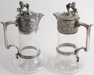 A matched pair of Edwardian silver, silver plated and cut glass claret jugs, by Elkington and Co, each with a lion and shield finial, angular thumb mould handle, and repousse decorated tops decorated with vine leaves and grapes with shaped spouts and bell