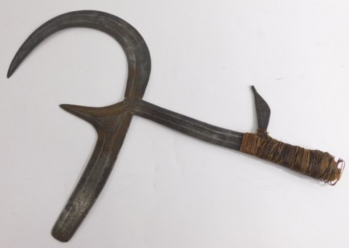 An African Kpinga throwing knife, with shaped elaborate blade and turned handle, 55cm high.