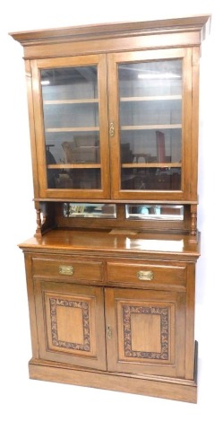 A late 19th/early 20thC oak dresser, the top with a moulded cornice above two glazed doors enclosing adjustable shelves and two bevel mirror plates, the base with two frieze drawers and two carved panelled doors, on a plinth, 221cm high, 112cm wide.