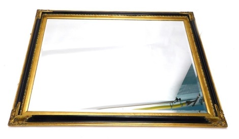 A 20thC ebonised and giltwood mirror, with bevelled glass and shell spandrels with an inner scroll moulding, 114cm high, 132cm wide, 7cm deep.