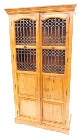 An Eastern hardwood cabinet, with a moulded cornice, above two pierced doors revealing wine rack, with panelled cupboards beneath on bracket feet, 172cm high, 94cm wide, 51cm deep.