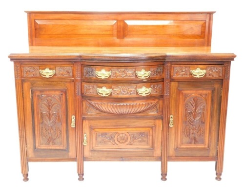 A Victorian walnut sideboard, the concave bowfront heavily carved with leaves and flower heads, centred by two drawers and a cupboard, flanked by two further drawers and double cupboards, on block stiles terminating in compressed circular feet, 122cm high