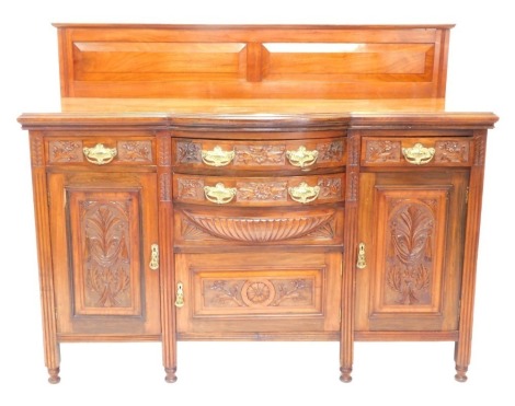 A Victorian walnut sideboard, the concave bowfront heavily carved with leaves and flower heads, centred by two drawers and a cupboard, flanked by two further drawers and double cupboards, on block stiles terminating in compressed circular feet, 122cm high