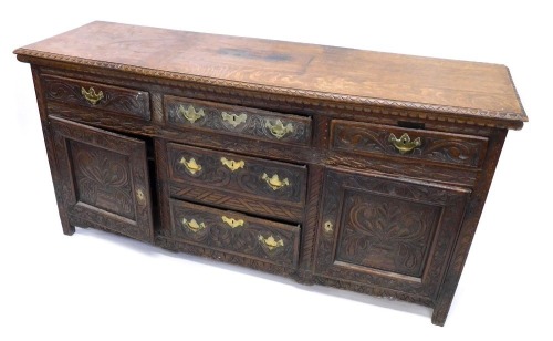 A Victorian oak sideboard, with part moulded top, raised above an arrangement of three central drawers flanked by two drawers and cupboards, each heavily carved with flowers and scrolls, on block stiles, 81cm high, 162cm wide, 46cm deep.