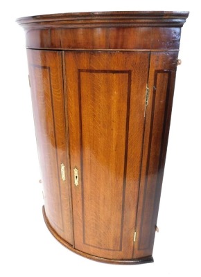 An early 19thC oak bowfront hanging corner cupboard, with fixed shelves, 104cm high, 71cm wide, 52cm deep.