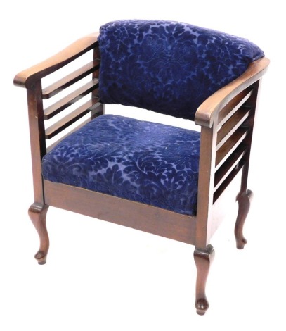 A 1920's armchair, with scroll arm supports upholstered in blue floral material to the back and seat, on squat cabriole front legs terminating in pad feet, 72cm high.