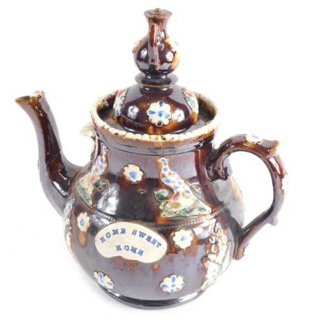 A Bargeware treacle glazed pottery teapot, with teapot knop, raised rosette and bird pattern, marked Home Sweet Home on circular foot, 34cm high.