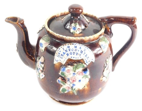 A Bargeware treacle glazed pottery teapot, raised with flowers marked Mrs J G May, Stanton Hill, Notts, 21cm high.