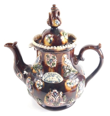 A Bargeware treacle glazed pottery teapot, the domed lid with teapot knop, the main body decorated with raised flowers and birds, predominantly in blue and pink with thumb mould handle, on circular foot, 43cm high.