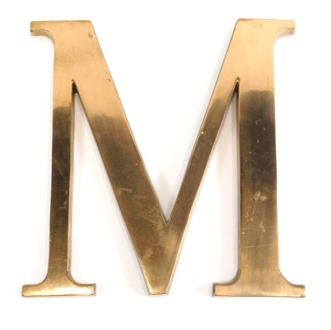 A metal shop sign M, in gilt metal, 31cm high.