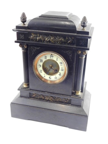 A 19thC black slate mantel clock, the 11cm diameter Arabic dial within an eight day movement, in a classical case flanked by columns, surmounted by acorn finials, with a raised classical section of cherubs and other figures to the upper and lower sections